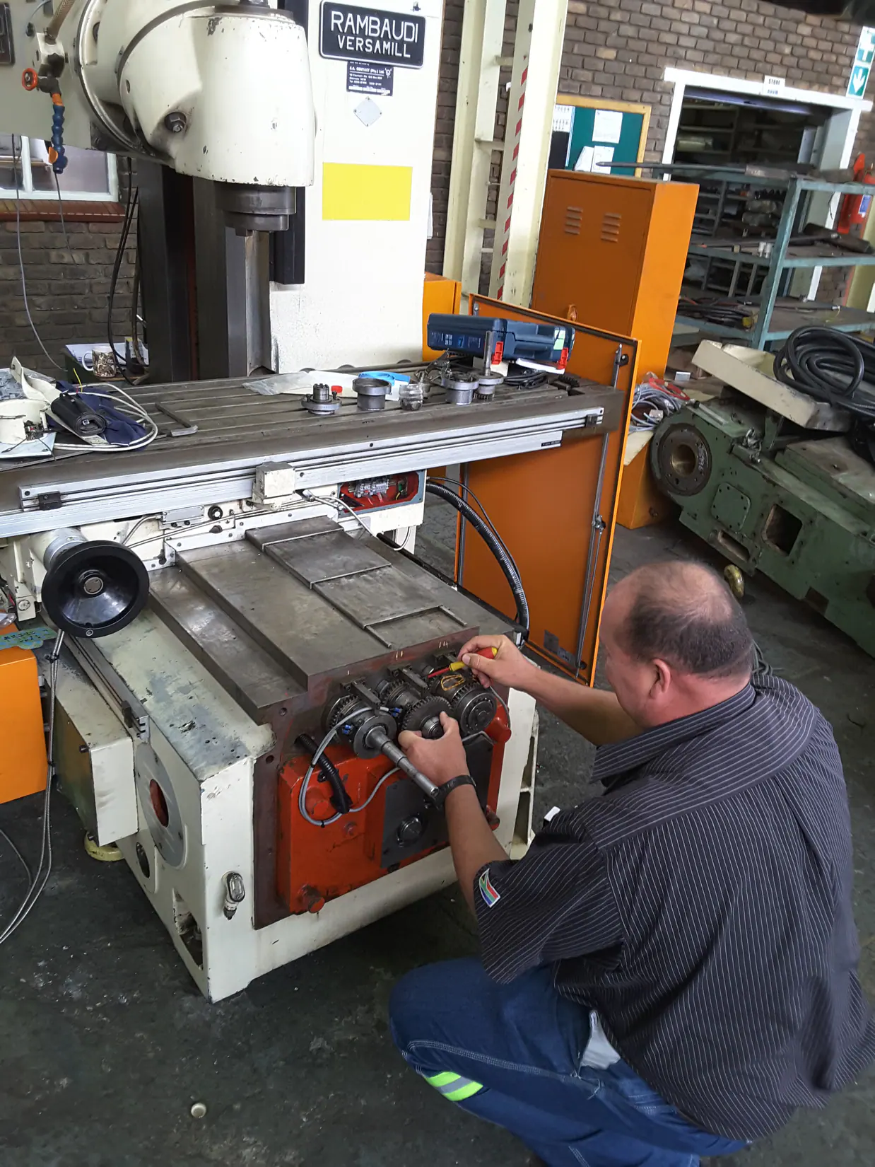 Field-service technician diagnosing a machine mechanism